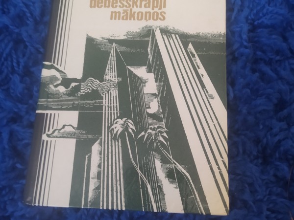 Kļavas lapa sniegā, debesskrāpji mākoņos